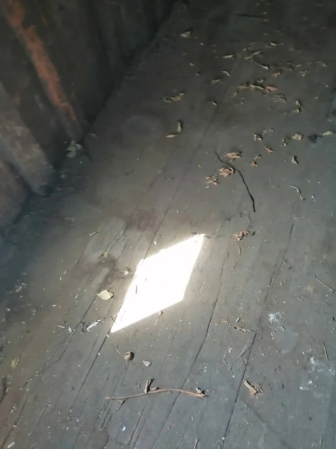 Photographie de la projection d'un losange lumineux sur le plancher du grenier.