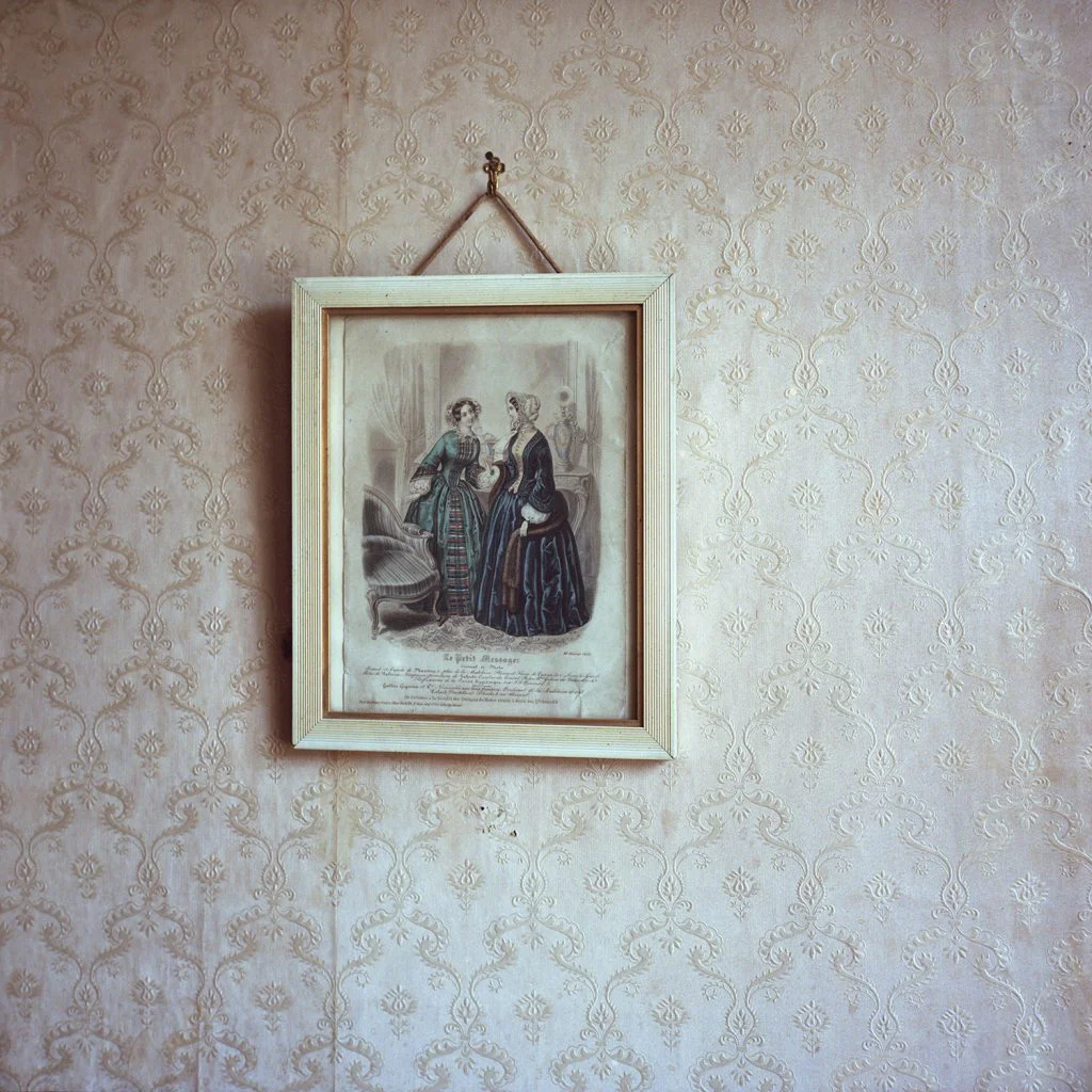 Photographie d'une illustration ancienne encadrée et accrochée au mur, représentant deux femmes en conversation