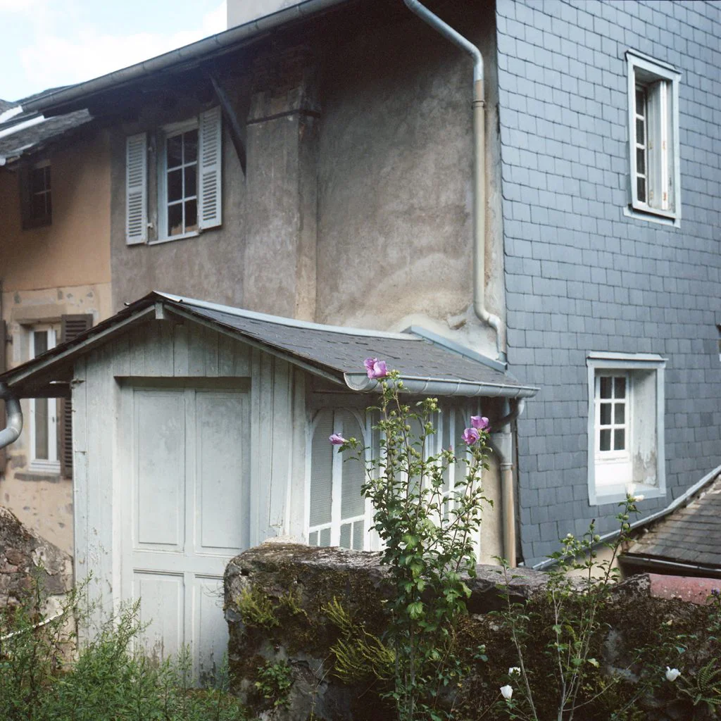 Photographie de la passerelle couverte à l'arrière de la maison donnant sur le jardin.